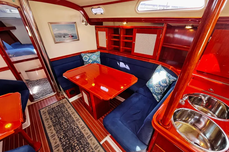 Slide: The Image of Luxurious 2004 Hanse 411 yacht interior with polished wood, blue seating, and elegant dining area. - 5