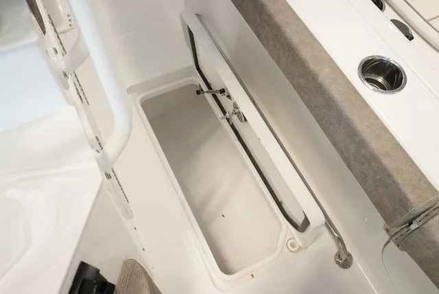 Slide: The Image of An open storage compartment on a Sea Hunt Ultra 265SE boat, featuring gray upholstery and stainless steel fittings. - 23