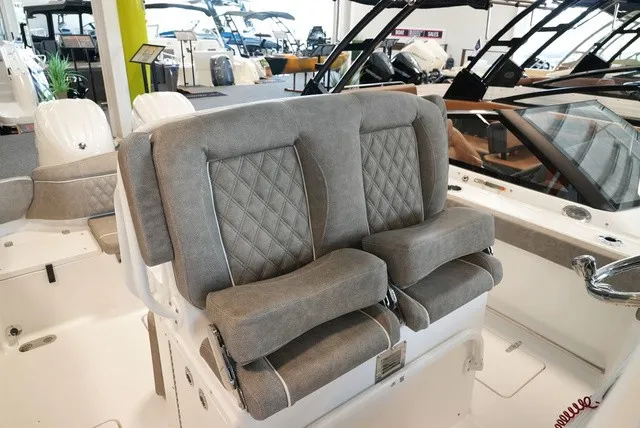 Slide: The Image of The 2027 Sea Hunt Ultra 265SE features luxurious, cushioned seats with a quilted design in a modern showroom. - 28