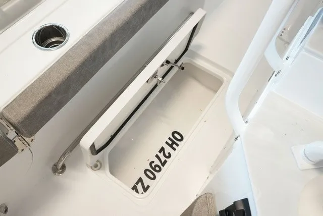 Slide: The Image of An open storage compartment on a boat with gray upholstery and a cup holder. - 22
