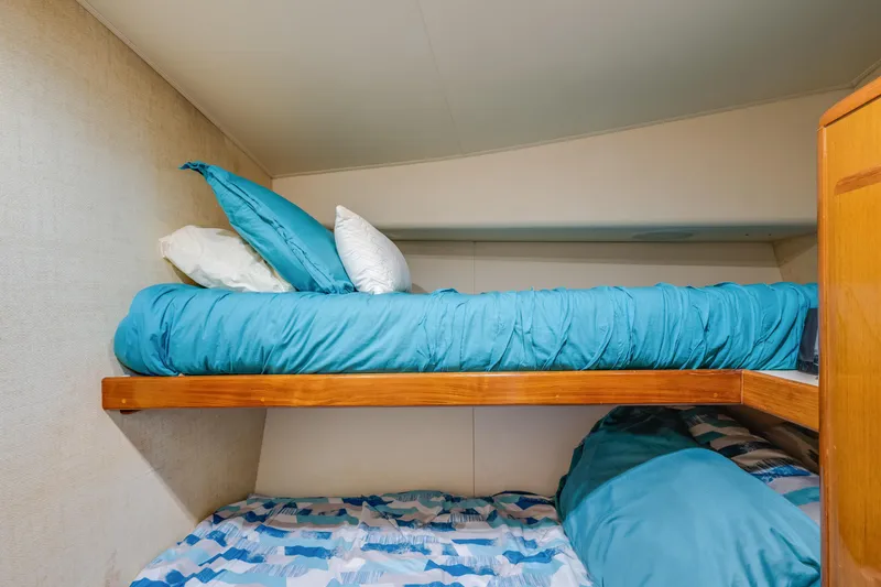 Slide: The Image of Bunk beds with blue bedding in a 1999 Viking 47 Convertible yacht cabin. - 26