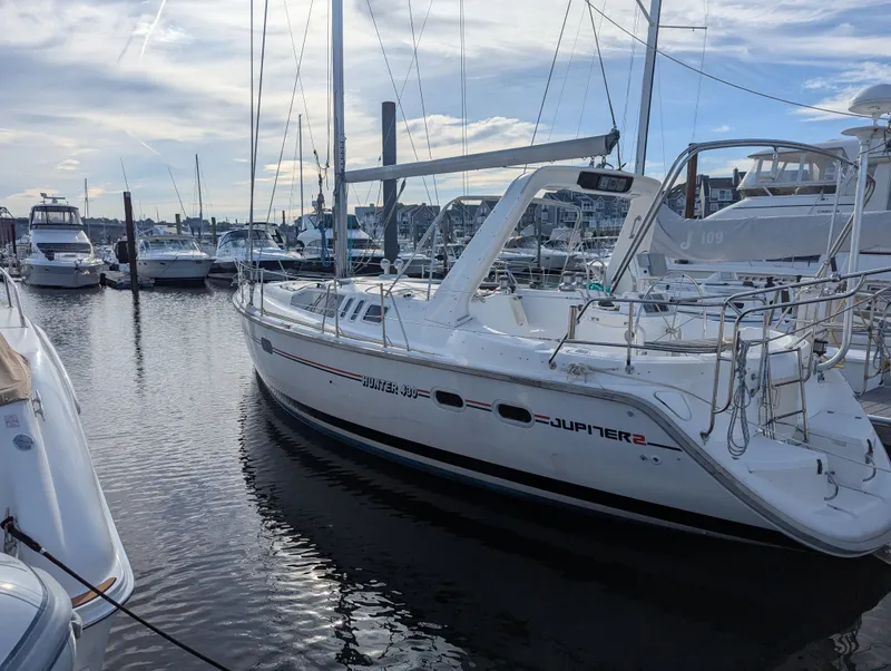 Slide: The Image of 1997 Hunter Sloop docked in marina, calm water, cloudy sky. - 2