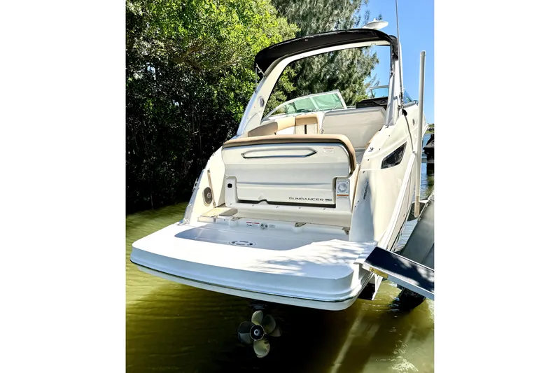 Slide: The Image of 2018 Sea Ray Sundancer 260 boat docked, rear view with lush greenery background. - 1