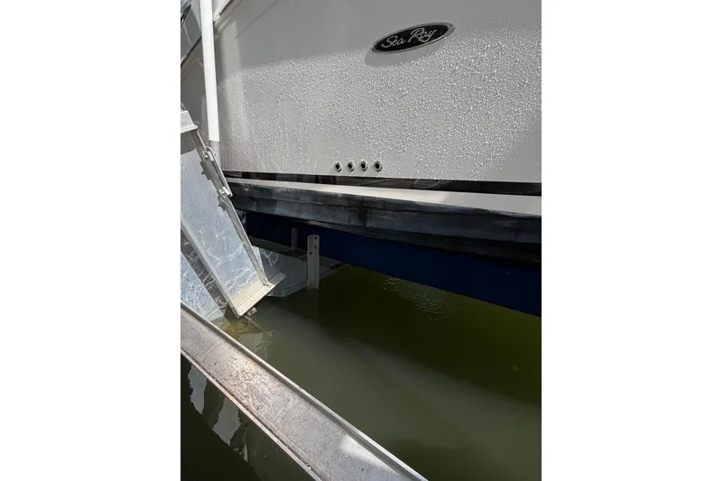 Slide: The Image of 2018 Sea Ray Sundancer 260 boat docked, showing hull and water reflection. - 14