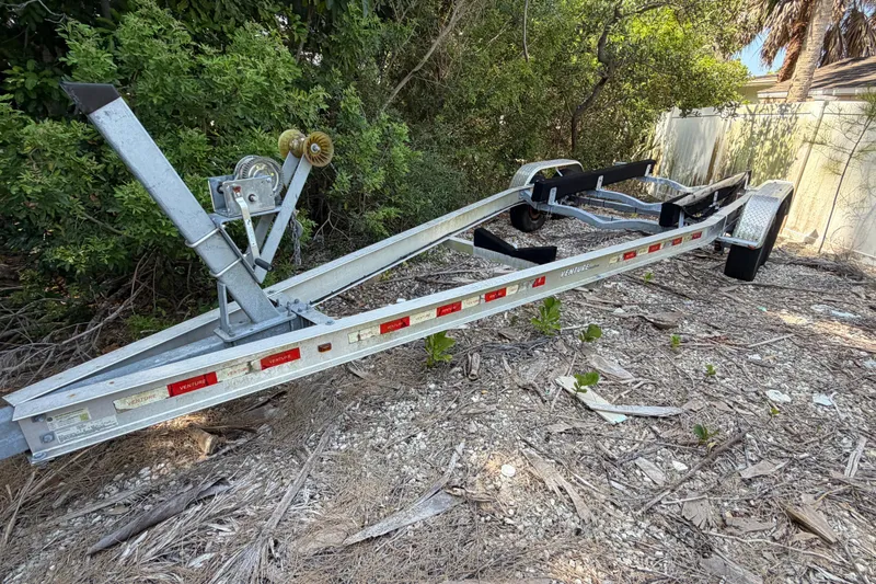 Slide: The Image of Boat trailer for 2018 Sea Ray Sundancer 260, parked on gravel near trees. - 21