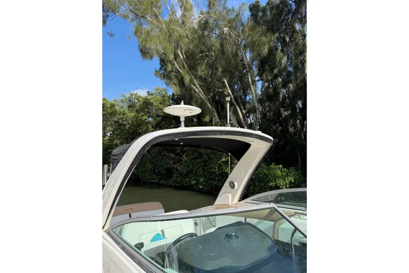 Slide: The Image of 2018 Sea Ray Sundancer 260 boat with canopy, surrounded by lush greenery and clear blue sky. - 38