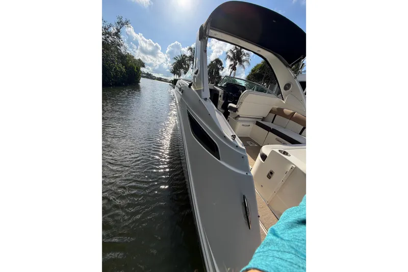 Slide: The Image of 2018 Sea Ray Sundancer 260 boat on a sunny waterway, showcasing sleek design and spacious seating. - 61