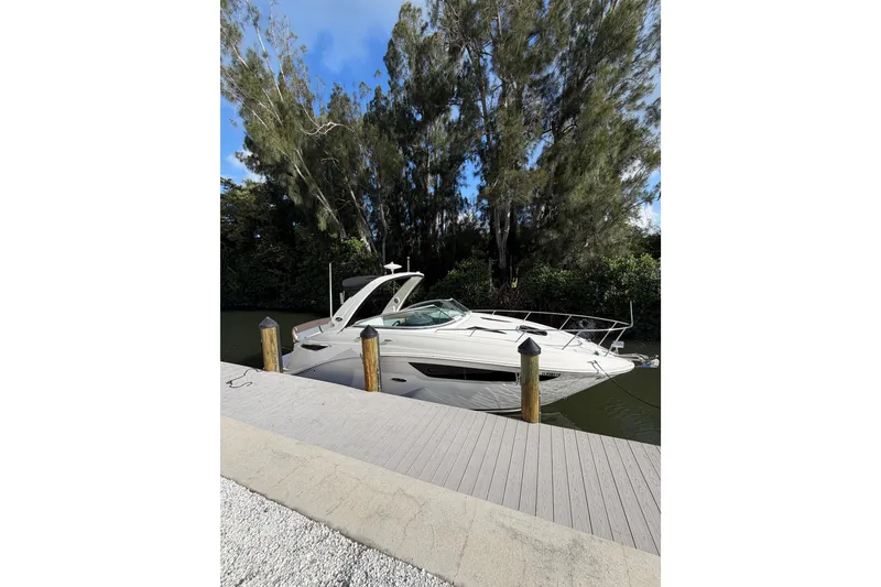 Slide: The Image of 2018 Sea Ray Sundancer 260 docked by a wooden pier, surrounded by lush trees. - 65