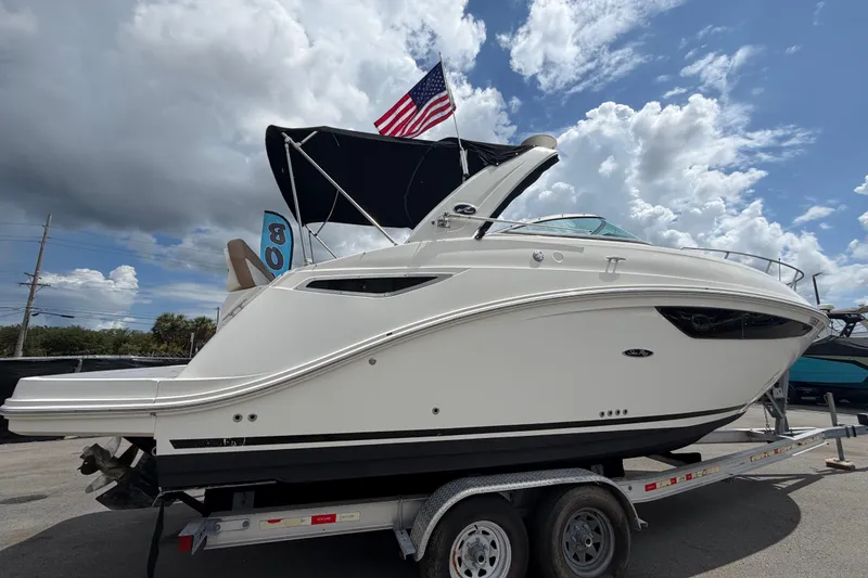 Slide: The Image of 2018 Sea Ray Sundancer 260 boat on trailer, under cloudy sky with American flag. - 2