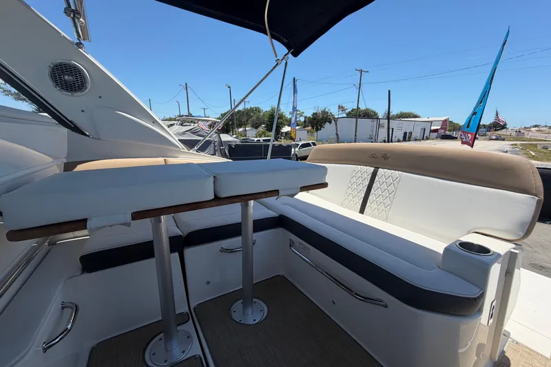 Slide: The Image of 2018 Sea Ray Sundancer 260 boat interior with cushioned seating and table under a clear sky. - 81