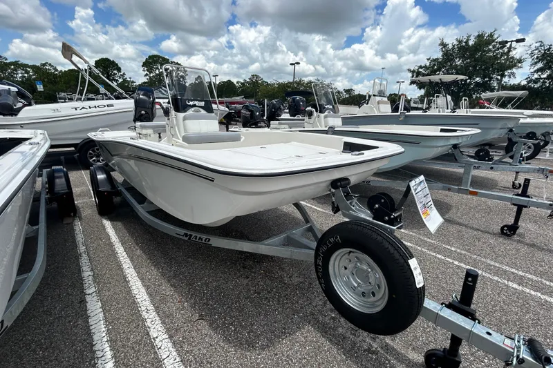 Slide: The Image of 2026 Mako Pro Skiff 15 CC boat on trailer in parking lot under cloudy sky. - 1