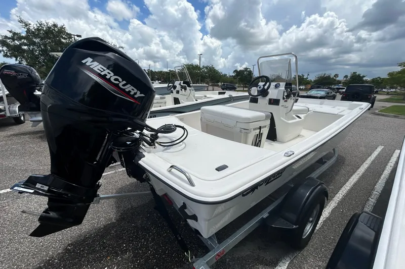 Slide: The Image of 2026 Mako Pro Skiff 15 CC boat with Mercury engine on trailer, parked outdoors. - 2