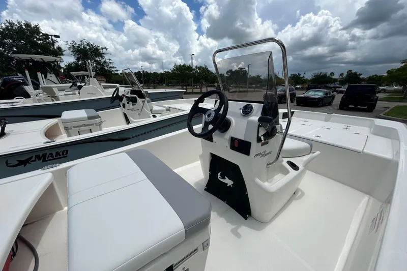 Slide: The Image of 2026 Mako Pro Skiff 15 CC boat with center console, parked outdoors under cloudy sky. - 4