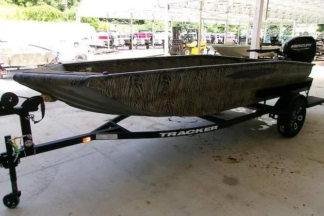 Slide: The Image of 2026 Tracker Grizzly 1650 T Prairie Wings Edition boat on trailer, camo design, parked indoors. - 3