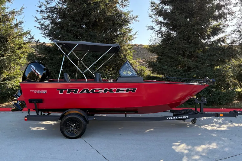 The Image of 2026 Tracker Pro Guide V-175 WT boat, red exterior, parked on trailer, surrounded by trees. - 0