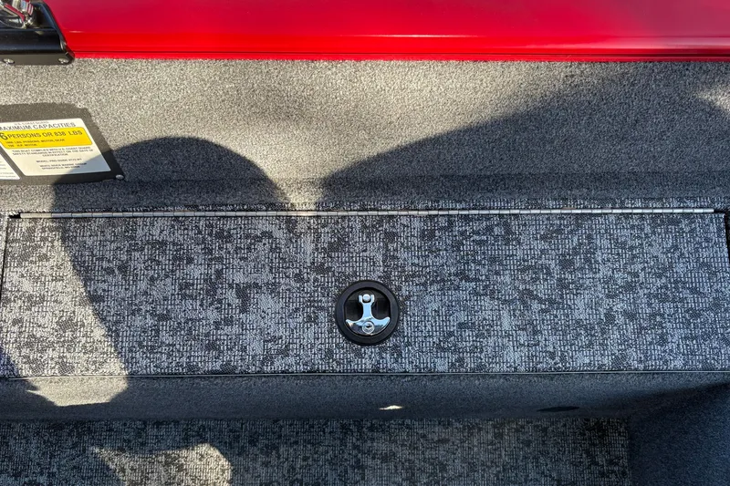 Slide: The Image of 2026 Tracker Pro Guide V-175 WT boat storage compartment with textured gray carpet and red trim. - 37