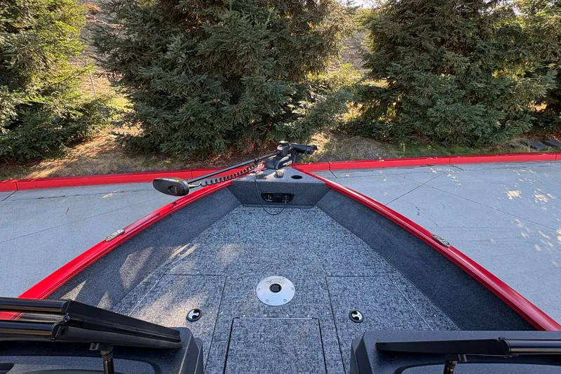 Slide: The Image of 2026 Tracker Pro Guide V-175 WT boat with red trim, parked near trees. - 16