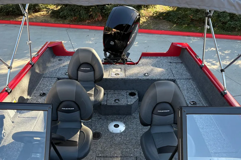 Slide: The Image of 2026 Tracker Pro Guide V-175 WT boat interior with seating and motor, parked outdoors. - 17