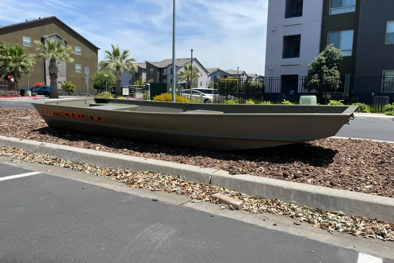 Slide: The Image of 2026 Tracker Grizzly 14 Jon boat displayed outdoors near residential buildings. - 2