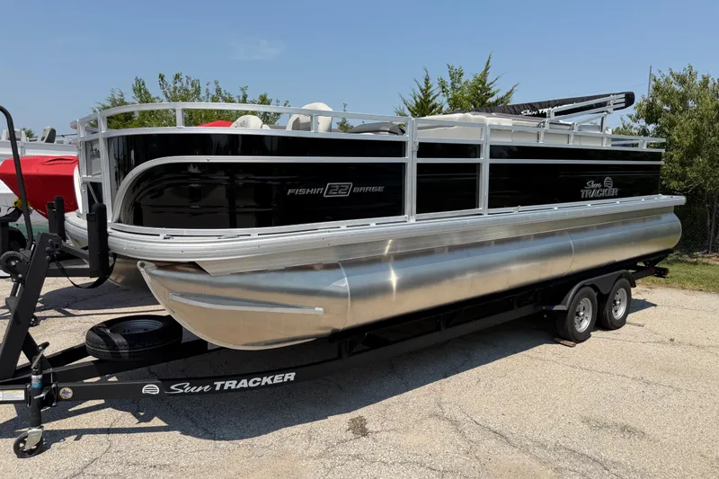 The Image of 2026 Sun Tracker Fishin' Barge 22 DLX pontoon boat on trailer, parked outdoors. - 0