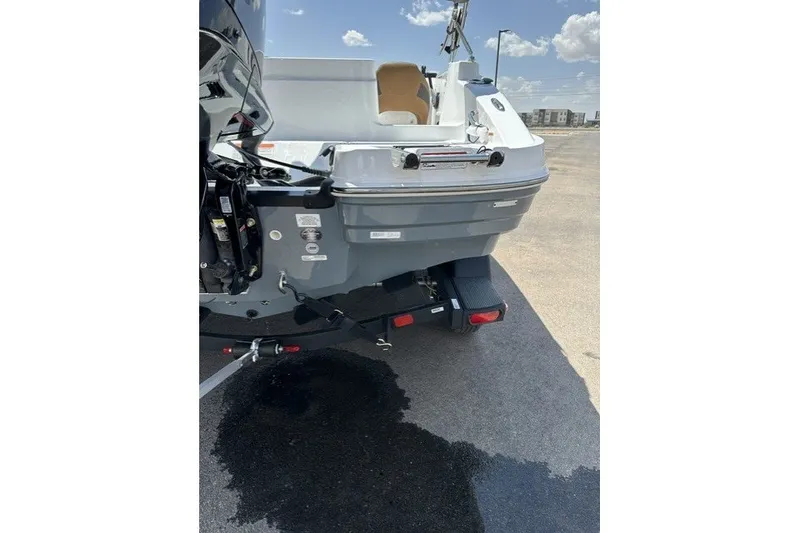 Slide: The Image of 2026 Tahoe 1950 boat rear view with trailer, parked on asphalt under blue sky. - 26