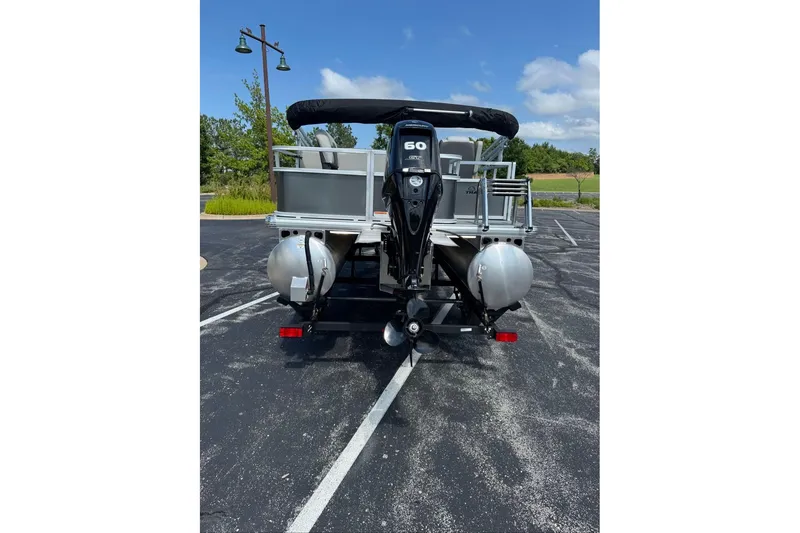 Slide: The Image of 2026 Sun Tracker Bass Buggy 18 DLX pontoon boat, rear view, parked outdoors. - 94