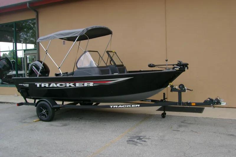 Slide: The Image of 2026 Tracker Pro Guide V-16 WT boat with canopy on trailer, parked outdoors. - 2