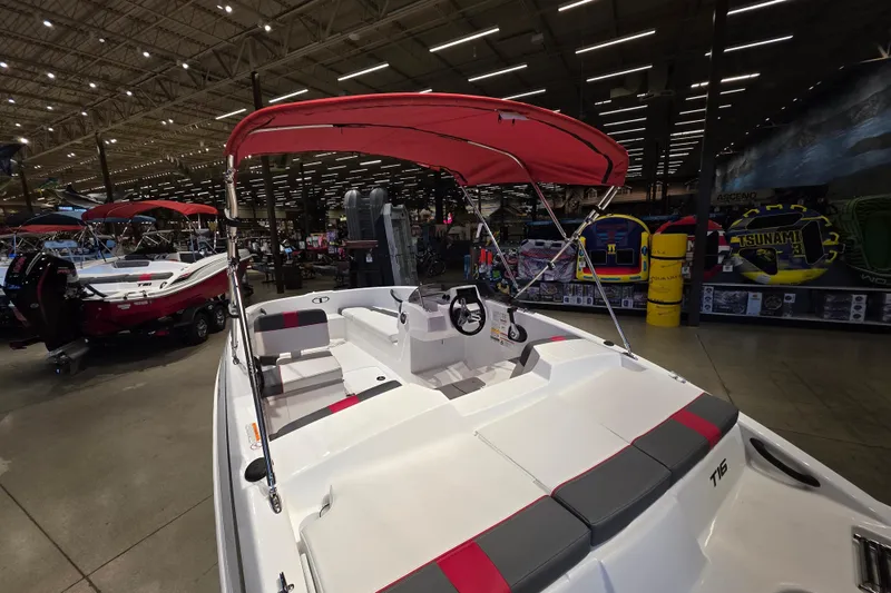 Slide: The Image of 2026 Tahoe T16 boat with red canopy displayed in a showroom. - 2
