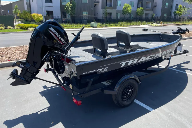 Slide: The Image of 2026 Tracker Super Guide V-16 T boat with Mercury motor in parking lot. - 2