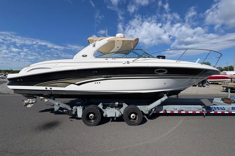 The Image of 2001 Sea Ray 290 Sun Sport boat on trailer under blue sky. - 0