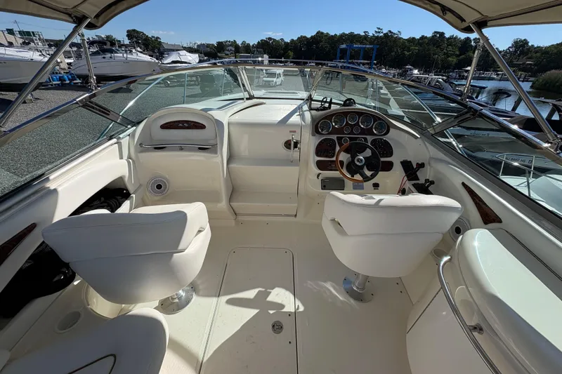 Slide: The Image of 2001 Sea Ray 290 Sun Sport boat interior with dual white captain chairs and control dashboard. - 12