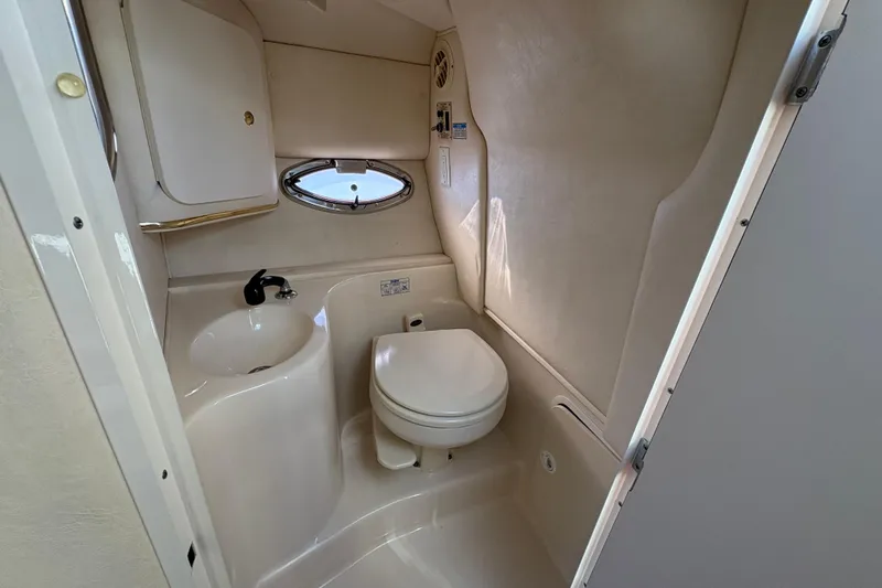 Slide: The Image of 2001 Sea Ray 290 Sun Sport boat bathroom with sink, toilet, and porthole window. - 17