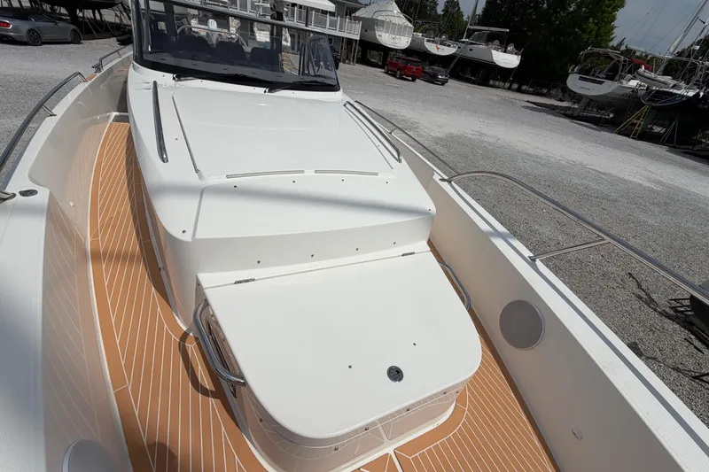 Slide: The Image of 2025 Nimbus Tender 11 boat with sleek white deck and wood accents in a marina setting. - 28