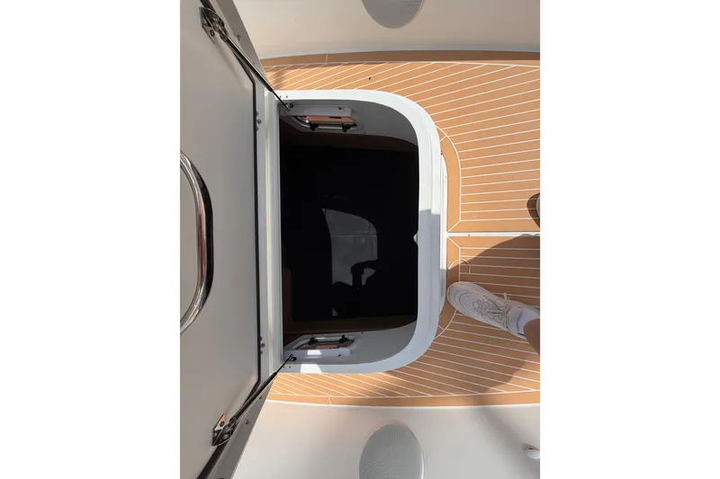 Slide: The Image of Open hatch on 2025 Nimbus Tender 11 boat with wooden deck and visible footwear. - 29