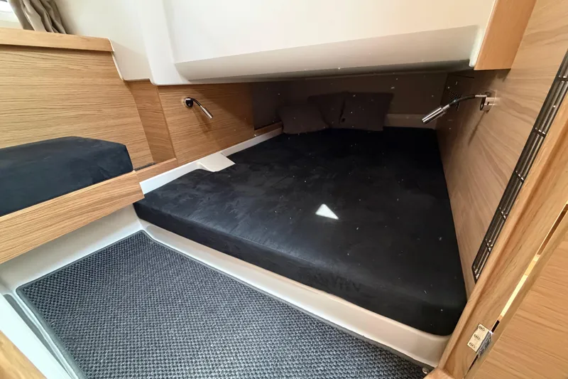Slide: The Image of Cozy cabin interior of 2025 Nimbus Tender 11 with wooden accents and black bedding. - 33