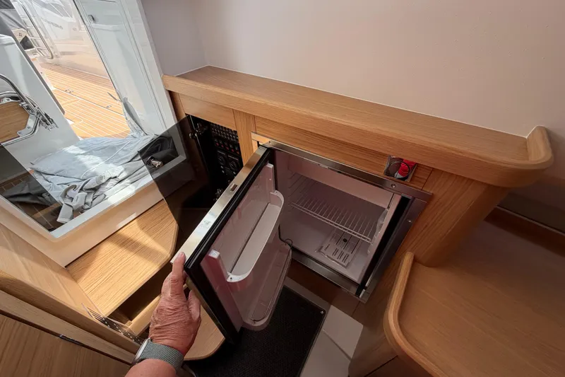 Slide: The Image of Open mini fridge in 2025 Nimbus Tender 11 yacht interior, showcasing modern wooden cabinetry. - 40