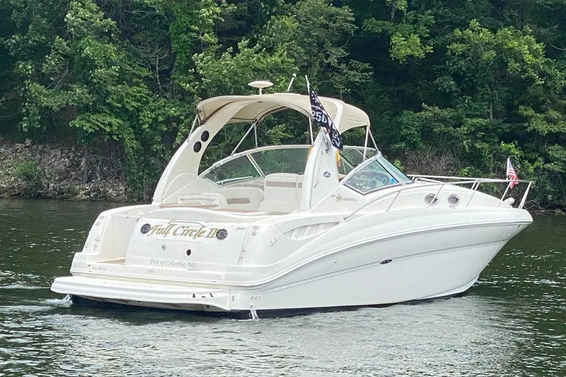 Slide: The Image of 2003 Sea Ray Sundancer 320 boat cruising on a lake with lush green trees. - 2