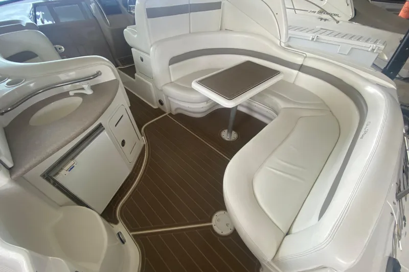 Slide: The Image of 2003 Sea Ray Sundancer 320 interior with white seating, compact table, and kitchenette. - 26