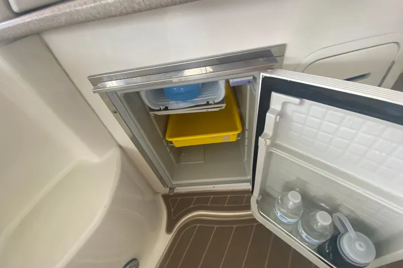 Slide: The Image of Mini fridge inside 2003 Sea Ray Sundancer 320 yacht, open with water bottles and storage. - 28