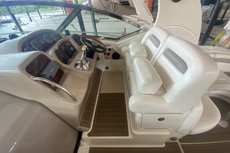 Slide: The Image of 2003 Sea Ray Sundancer 320 helm with white seating and wood-accented dashboard. - 32