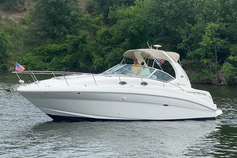 Slide: The Image of 2003 Sea Ray Sundancer 320 cruising on a serene lake with lush green surroundings. - 5