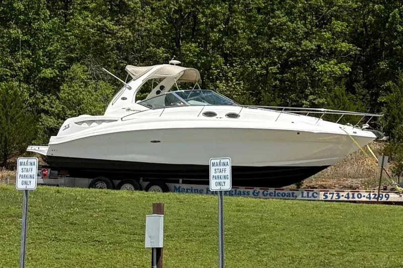 Slide: The Image of 2003 Sea Ray Sundancer 320 boat on trailer, parked near marina, surrounded by greenery. - 36