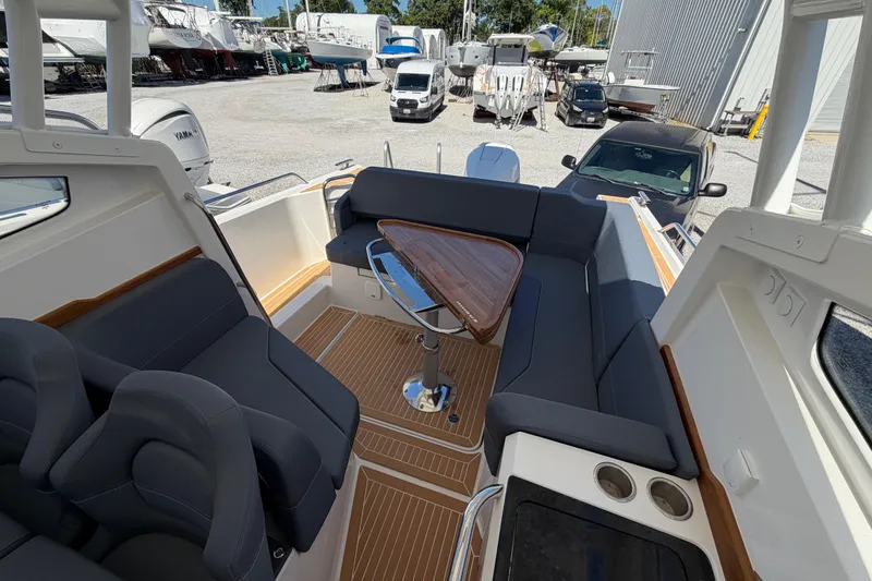 Slide: The Image of 2025 Nimbus Weekender 9 boat interior with sleek seating and wooden table in a marina setting. - 5