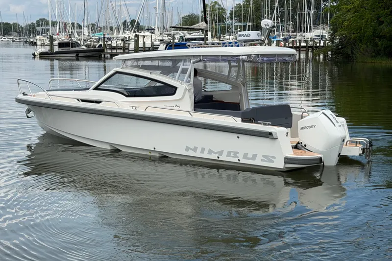 Slide: The Image of 2025 Nimbus Weekender 9 boat docked in a marina with Mercury engine. - 1