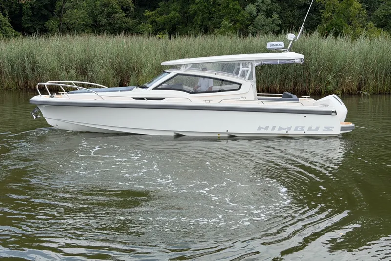 Slide: The Image of 2025 Nimbus Weekender 9 boat cruising on a calm river with lush greenery. - 2