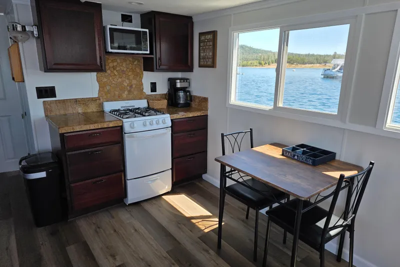Slide: The Image of Cozy 2007 custom houseboat kitchen with lake view, featuring stove, microwave, and dining area. - 10