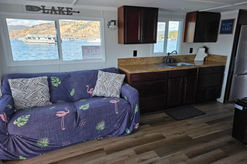 Slide: The Image of Interior of a 2007 custom houseboat with cozy seating and kitchen area, overlooking a scenic lake. - 11