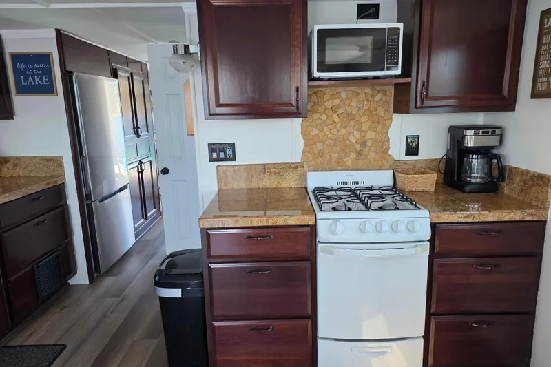 Slide: The Image of Houseboat kitchen interior with wooden cabinets, stove, microwave, and coffee maker, 2007 model. - 12