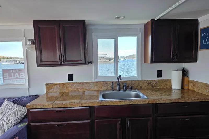 Slide: The Image of Houseboat kitchen interior with dark cabinets, granite countertops, and a window view of the water. - 13