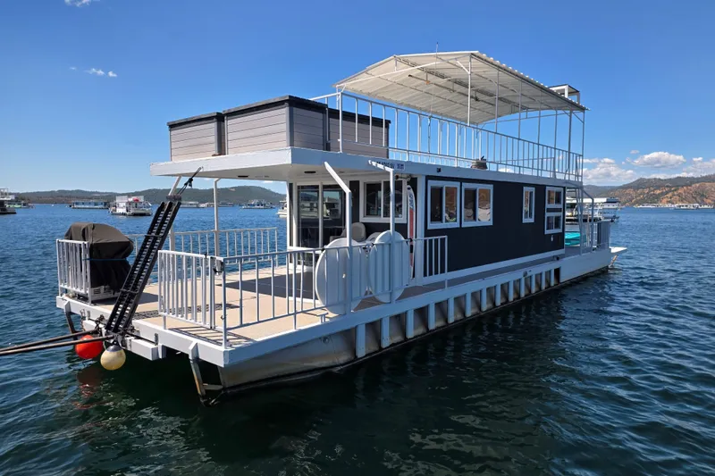 Slide: The Image of Custom 2007 houseboat on serene lake with upper deck and scenic mountain backdrop. - 2